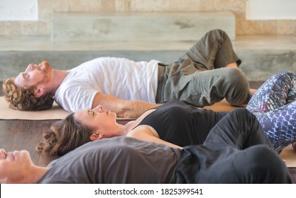 Diverse group of people on wooden floor practicing yoga lying in Reclined Butterfly exercise relaxing after practice. Healthy lifestyle concept