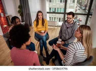 Diverse Group Of People Sitting In Circle In Group Therapy Session.