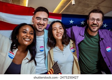 A diverse group of people stands proudly together, each holding a small American flag in one hand and displaying an "I Voted" sticker on their clothing. The group represents various ages, ethnicities, - Powered by Shutterstock