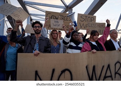 Diverse group of people united to protest against the war holding up banners and raising fits manifesting discomfort and standing for peace. - Powered by Shutterstock