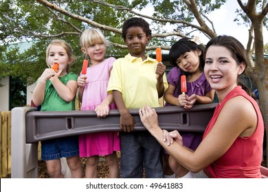 Diverse Group Of Preschool 5 Year Old Children Playing In Daycare With Teacher