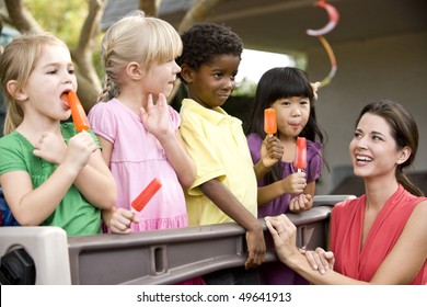 Diverse Group Of Preschool 5 Year Old Children Playing In Daycare With Teacher