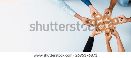 A diverse group of professionals collaborating hands-on with interlocking gears to represent management strategy and teamwork in a modern business setup. Amity