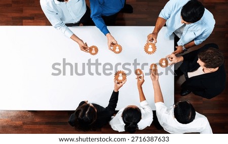 A diverse group of professionals engaging in collaborative teamwork using gear symbols, symbolizing innovation and strategic connections in a business networking environment. Amity