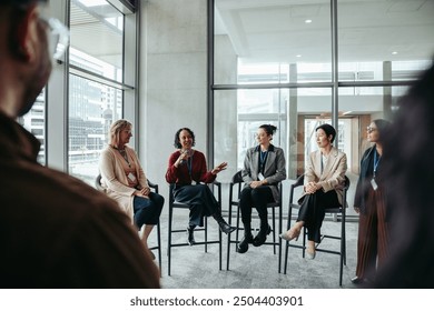 Diverse group of professionals engaging in a lively discussion, sharing expertise during a meeting in a modern office setting. - Powered by Shutterstock