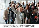 A diverse group of professionals taking a cheerful selfie together during a seminar or workshop. They are smiling and appear engaged.