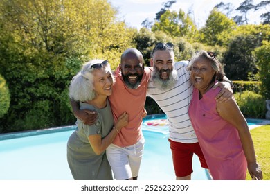 Diverse group of senior friends hugging and smiling by swimming pool outdoors. Friendship, leisure, bonding, happiness, retirement, summer, unaltered - Powered by Shutterstock