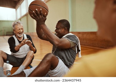 Diverse group of senior men taking a break from playing basketball in an indoor basketball gym - Powered by Shutterstock