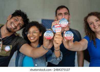 diverse group of smiling friends holding 2024 Vote election I voted buttons or pins at a US election polling station. In the background, american flag at the background, democracy in America USA - Powered by Shutterstock