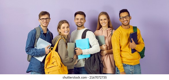 Diverse Group Of Smiling University Or College Students. Happy Multi Ethnic Young Friends In Casual Wear With Backpacks, Class Textbooks And Modern Laptop PCs Standing Together And Looking At Camera