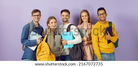 Diverse group of smiling university or college students. Happy multi ethnic young friends in casual wear with backpacks, class textbooks and modern laptop PCs standing together and looking at camera