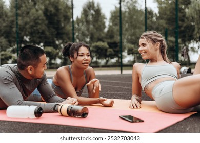 Diverse group of smiling young, attractive sportswomen and sportsman lying together on mat, relaxing after training. Team resting, sport, motivation concept - Powered by Shutterstock