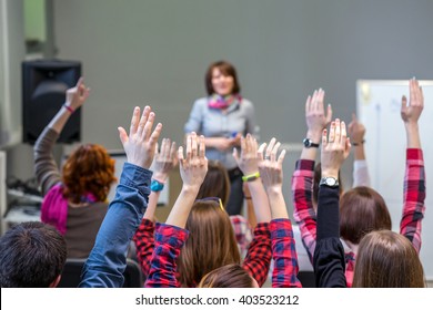Diverse Gruppe von Studenten im Konferenzsaal, die Waffen hochheben und aktiv am Seminar-Lehrergremium auf Hintergrund teilnehmen