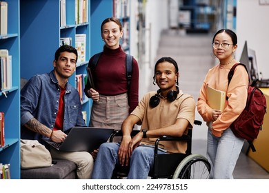 Diverse group of students with young man in wheelchair looking at camera in college library, inclusivity concept - Powered by Shutterstock