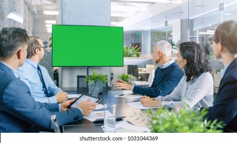 Diverse Group of Successful Business People in the Conference Room with  Green Screen Chroma Key TV on the Wall.  They Work on a Company's Growth, Share Charts and Statistics. - Powered by Shutterstock