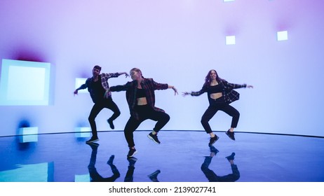 Diverse Group of Three Professional Dancers Performing a Hip Hop Dance Routine in Front of a Big Led Wall Screen with VFX Animation During a Virtual Production in Studio Environment. 105 BPM Song. - Powered by Shutterstock