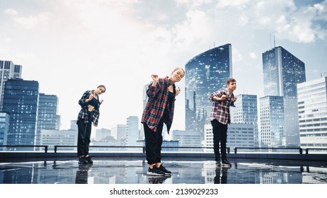 Diverse Group Of Three Professional Dancers Performing A Hip Hop Dance Routine In Front Of A Big Digital Led Wall Screen With Modern Urban Skyline With Office Skyscrapers In Studio Environment.