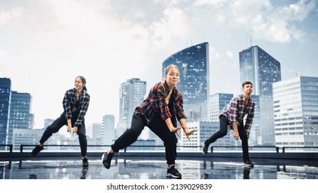 Diverse Group Of Three Professional Dancers Performing A Hip Hop Dance Routine In Front Of A Big Digital Led Wall Screen With Modern Urban Skyline With Office Skyscrapers In Studio Environment.