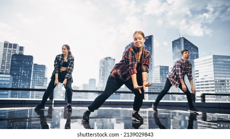 Diverse Group Of Three Professional Dancers Performing A Hip Hop Dance Routine In Front Of A Big Digital Led Wall Screen With Modern City Skyline With Office Skyscrapers In Studio Environment.