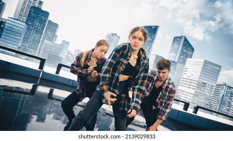 Diverse Group Of Three Young Professional Dancers Performing A Hip Hop Dance Routine In Close Up In Front Of A Big Led Screen With Modern Urban Skyline With Office Skyscrapers In Studio Environment.