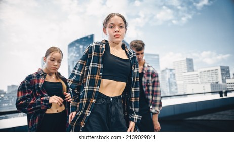 Diverse Group Of Three Young Professional Dancers Performing A Hip Hop Dance Routine In Close Up In Front Of A Big Led Screen With Modern Urban Skyline With Office Skyscrapers In Studio Environment.