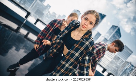 Diverse Group Of Three Young Professional Dancers Performing A Hip Hop Dance Routine In Close Up In Front Of A Big Led Screen With Modern Urban Skyline With Office Skyscrapers In Studio Environment.