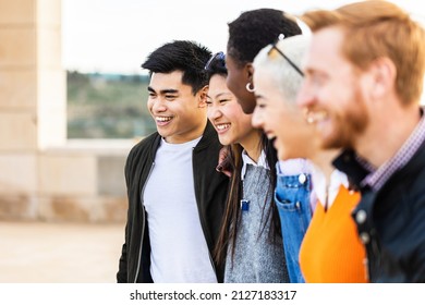 Diverse group of united young friends laughing together outdoor - Multiracial teenager students having fun hugging each other in street - Team, community and unity concept