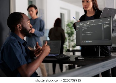 Diverse group of web developers analyzing html code and comparing data script in big data office room. Cloud programers working on system interface algorithm in development company.