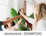 A diverse group of women, celebrate teamwork with high-fives. Joyful teamwork women high-fives. Group of businesswomen achievement high-fives. Cheerful diverse women team high-fives for achievement