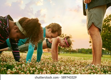 Diverse group of women during a fitness training doing push-ups at sunset in nature park - Powered by Shutterstock