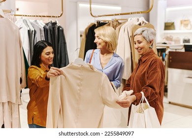 Diverse group of women shopping for clothes in luxury boutique and looking at blouses - Powered by Shutterstock