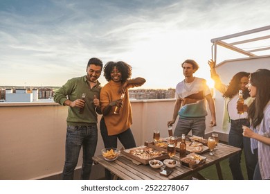 Diverse group of young adults having fun with drinks and pizza at a sunset rooftop gathering. - Powered by Shutterstock