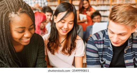 Diverse group of young adults studying together in a library. Smiling students, books, and learning. Multicultural, collaborative, and educational environment. Diverse young people reading at library. - Powered by Shutterstock