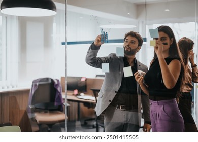 A diverse group of young business professionals engaging in a brainstorming session using sticky notes on a glass wall to analyze growth, statistics, and strategies. - Powered by Shutterstock