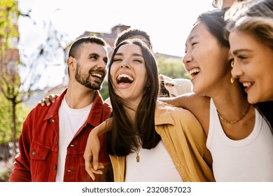 Diverse group of young friends having fun together outdoors in summer. Millennial student people laughing walking in city street enjoying day off. Youth community and friendship concept. - Powered by Shutterstock