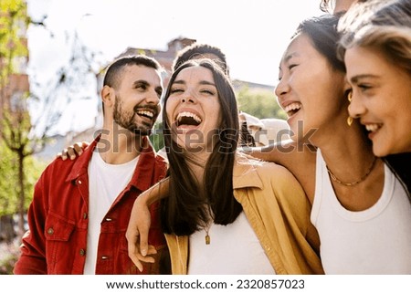 Diverse group of young friends having fun together outdoors in summer. Millennial student people laughing walking in city street enjoying day off. Youth community and friendship concept.