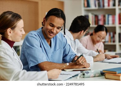 Diverse group of young medical professionals at table during meeting or seminar