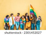 Diverse group of young people celebrating gay pride festival day - Lgbt community concept with guys and girls hugging together outdoors - Multiracial trendy friends standing on a yellow background 