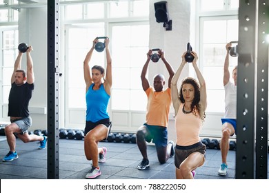 Diverse Group Of Young People Doing Lunges With Weights In A Gym Together During A Workout