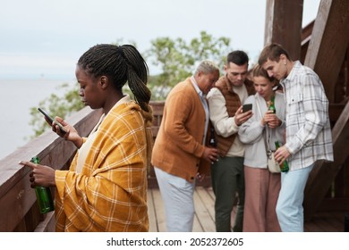 Diverse Group Young People Relaxing On Balcony During Party At Lake House