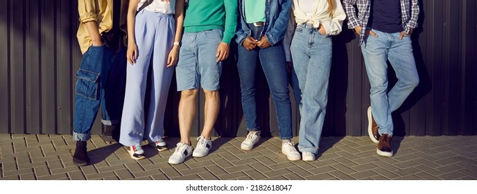 Diverse group of young people wearing jeans. Six men and women in comfortable blue jeans, shorts, and trendy sneakers leaning on street wall. Banner, crop shot, human legs. Casual city fashion concept - Powered by Shutterstock