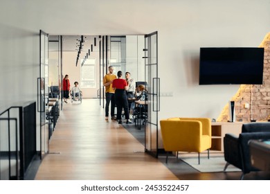 A diverse group of young professionals, including businesswomen and an African-American entrepreneur in a wheelchair, engage in collaborative discussion on various business projects in a modern - Powered by Shutterstock