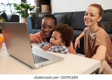 Diverse Lesbian Couple And Little Son Watching Animated Cartoon On Laptop At Home