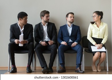 Diverse male applicants looking at female rival among men waiting for at job interview, professional career inequality, employment sexism prejudice, unfair gender discrimination at work concept