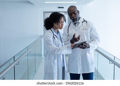 Diverse male and female doctor talking seriously and looking at digital tablet in hospital corridor. medicine, health and healthcare services. - Powered by Shutterstock