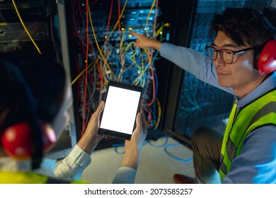 Diverse Male And Female Engineer Using Digital Tablet While Inspecting In Computer Server Room. Database Server Management And Maintenance Concept