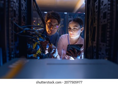 Diverse Male And Female Engineers With Digital Tablet Inspecting The Server In Computer Server Room. Database Server Management And Maintenance Concept