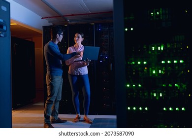 Diverse male and female engineers using laptop in computer server room. database server management and maintenance concept - Powered by Shutterstock