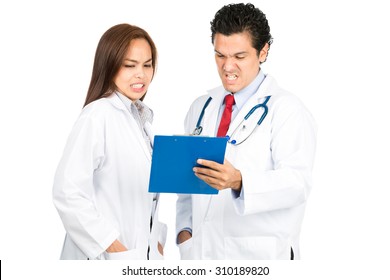 A Diverse Male, Female, Hispanic, Asian Team Of Doctors Reviewing Medical Charts Together Grimacing With Shocked, Pained Reaction, Horrified At Bad Diagnosis. Horizontal