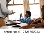 Diverse male teacher teaching school boy using sign language in class at elementary school. School, disability and education, unaltered.